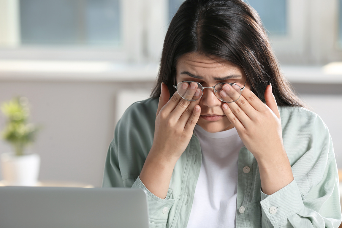 Young Woman Suffering from Eyestrain in Office